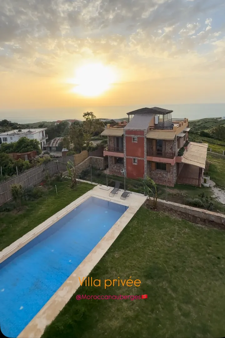 Villa avec piscine allongée et terrasse en toiture au coucher du soleil