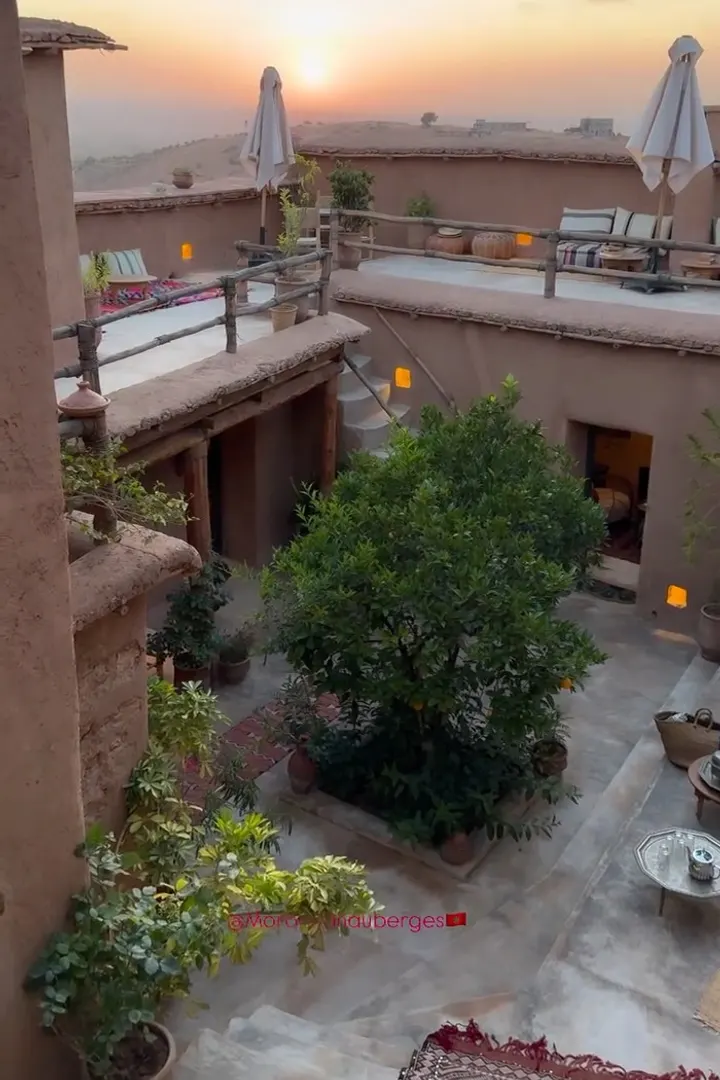 Cour intérieure en pisé avec un arbre et des terrasses au coucher du soleil