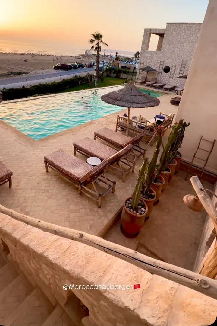 Terrasse en pierre surplombant la piscine et la plage au coucher du soleil