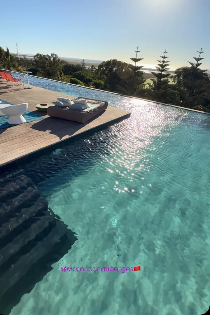 Piscine à débordement et terrasse en bois au coucher du soleil