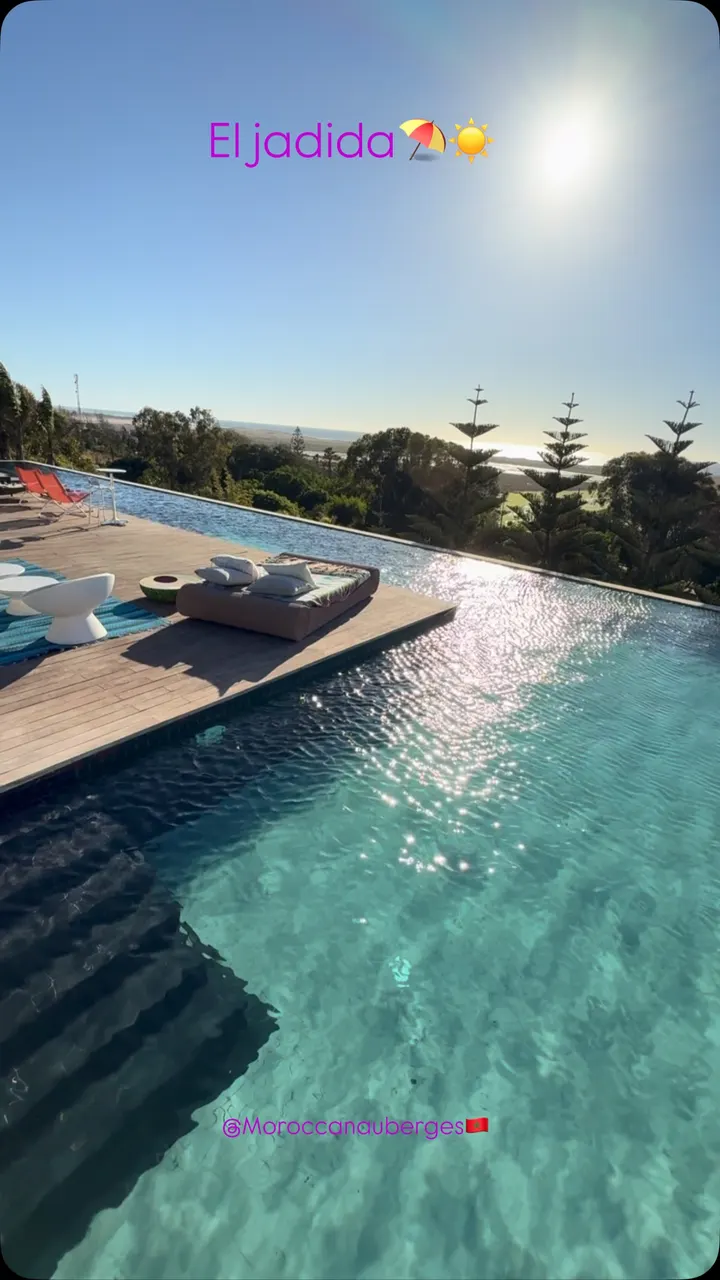 Piscine à débordement et terrasse en bois au coucher du soleil