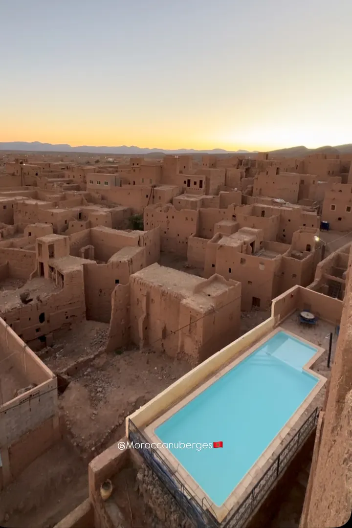 Piscine sur toit dominant un ksar en pisé au crépuscule