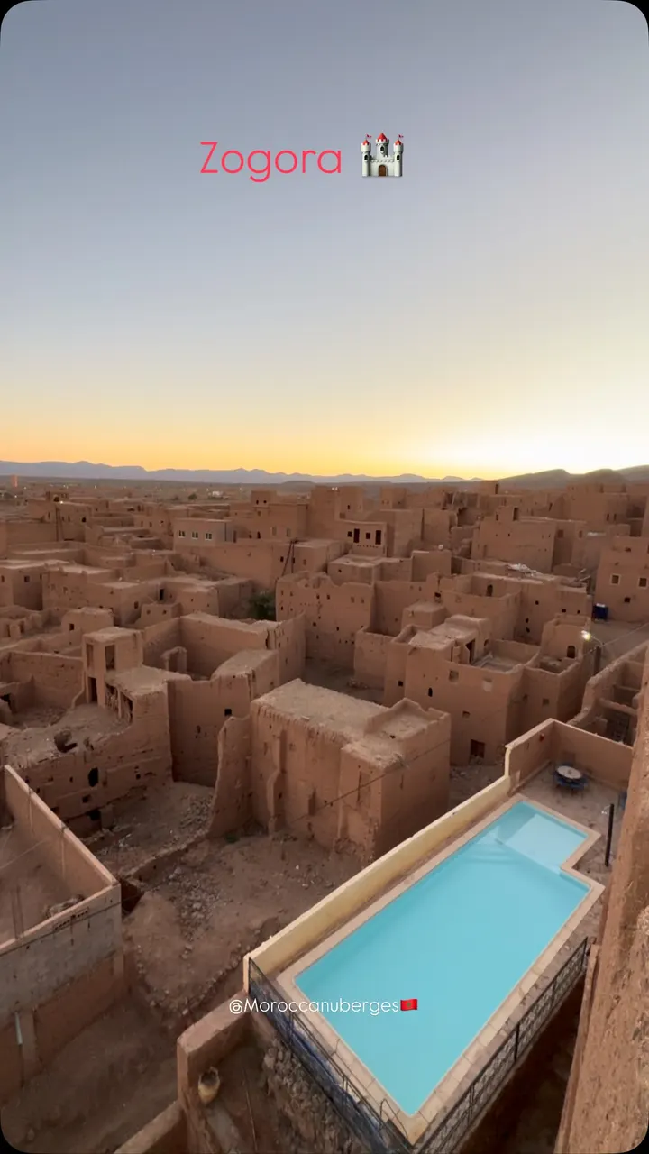 Piscine sur toit dominant un ksar en pisé au crépuscule