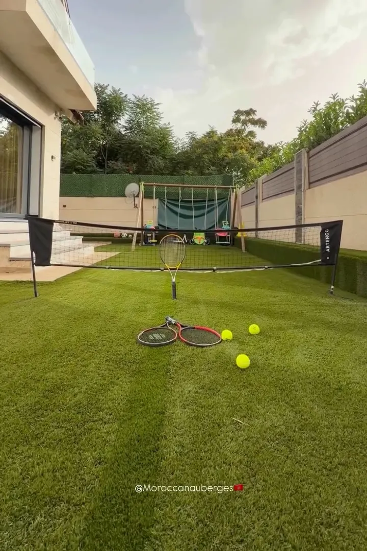 Jardin avec terrain de tennis et espace de jeux pour enfants
