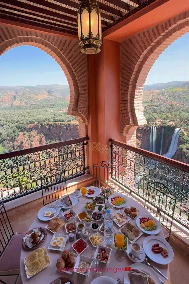 Terrasse sous deux arches en brique, table de petit-déjeuner dressée face aux cascades d’Ouzoud